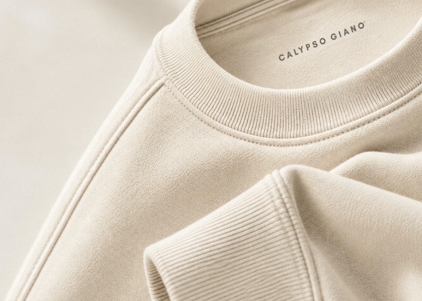 Nahaufnahme eines cremefarbenen CALYPSO GIANO Sweatshirts mit sichtbarer Stoffstruktur, Kragen und Bündchen