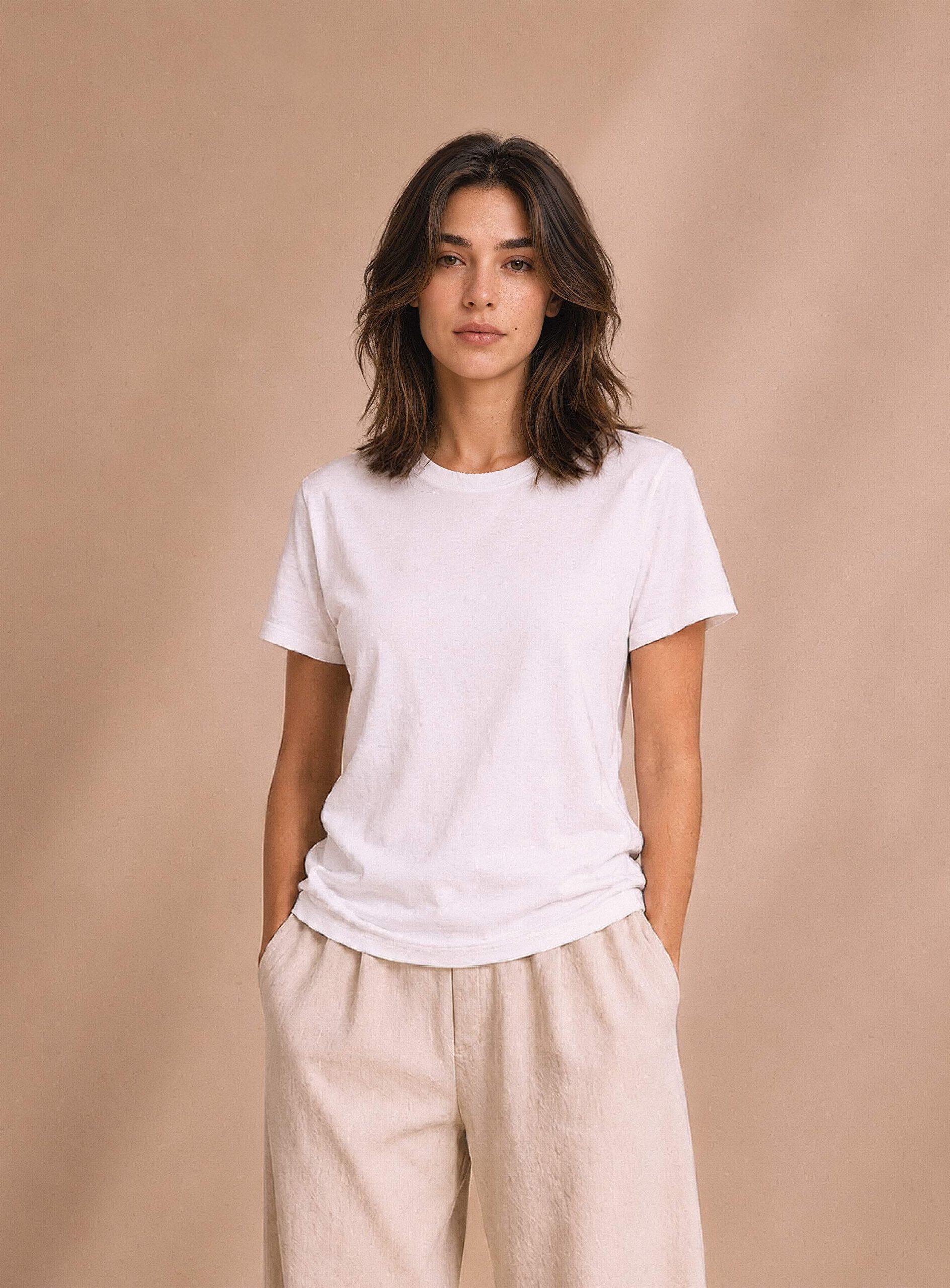 Damenmodel Mara in weißem T-Shirt und heller Hose vor beigem Hintergrund
